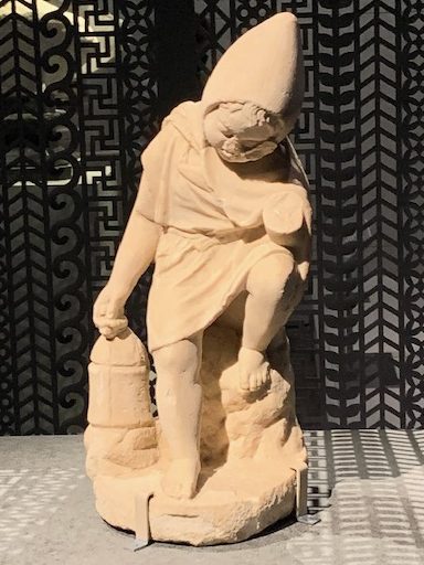 Statue of young bog wearing pointed hood of cape over head