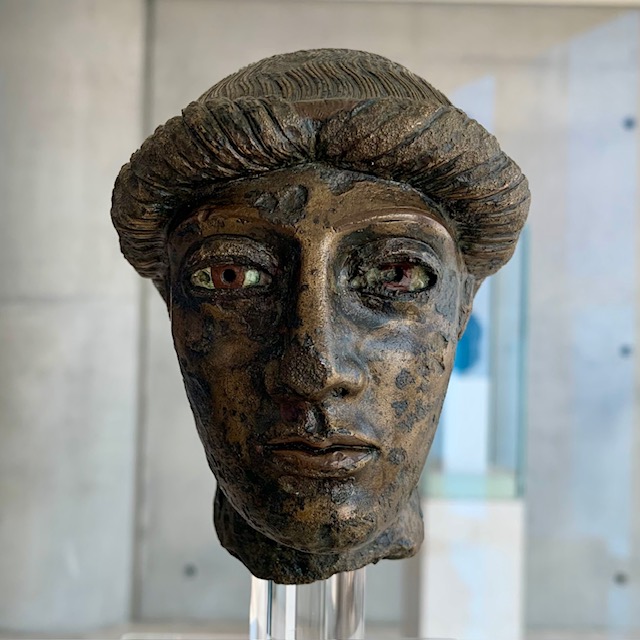 Bronze sculpture of young man's head.