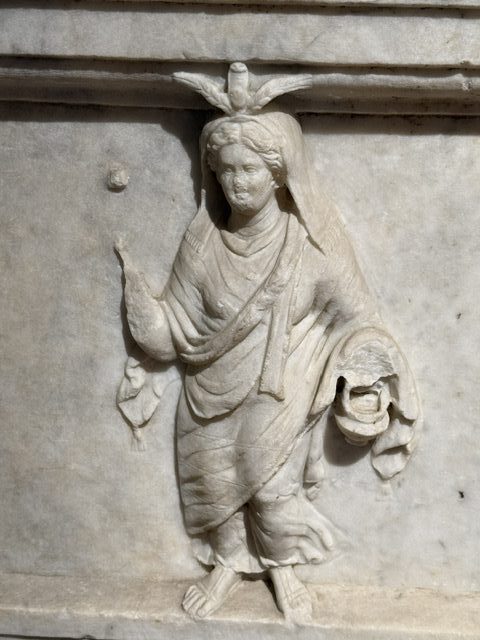 Detail from an altar showing the goddess Isis holding her ritual items, a vase and sistrum rattle (now missing)